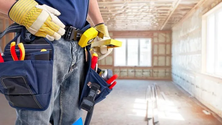 Electrician with a tool belt in a room being renovated